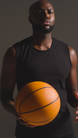 Vertical-Video-Studio-Vertical-Video-Portrait-Shot-Of-Male-Basketball-Player-Throwing-Ball-From-One-Hand-To-The-Other